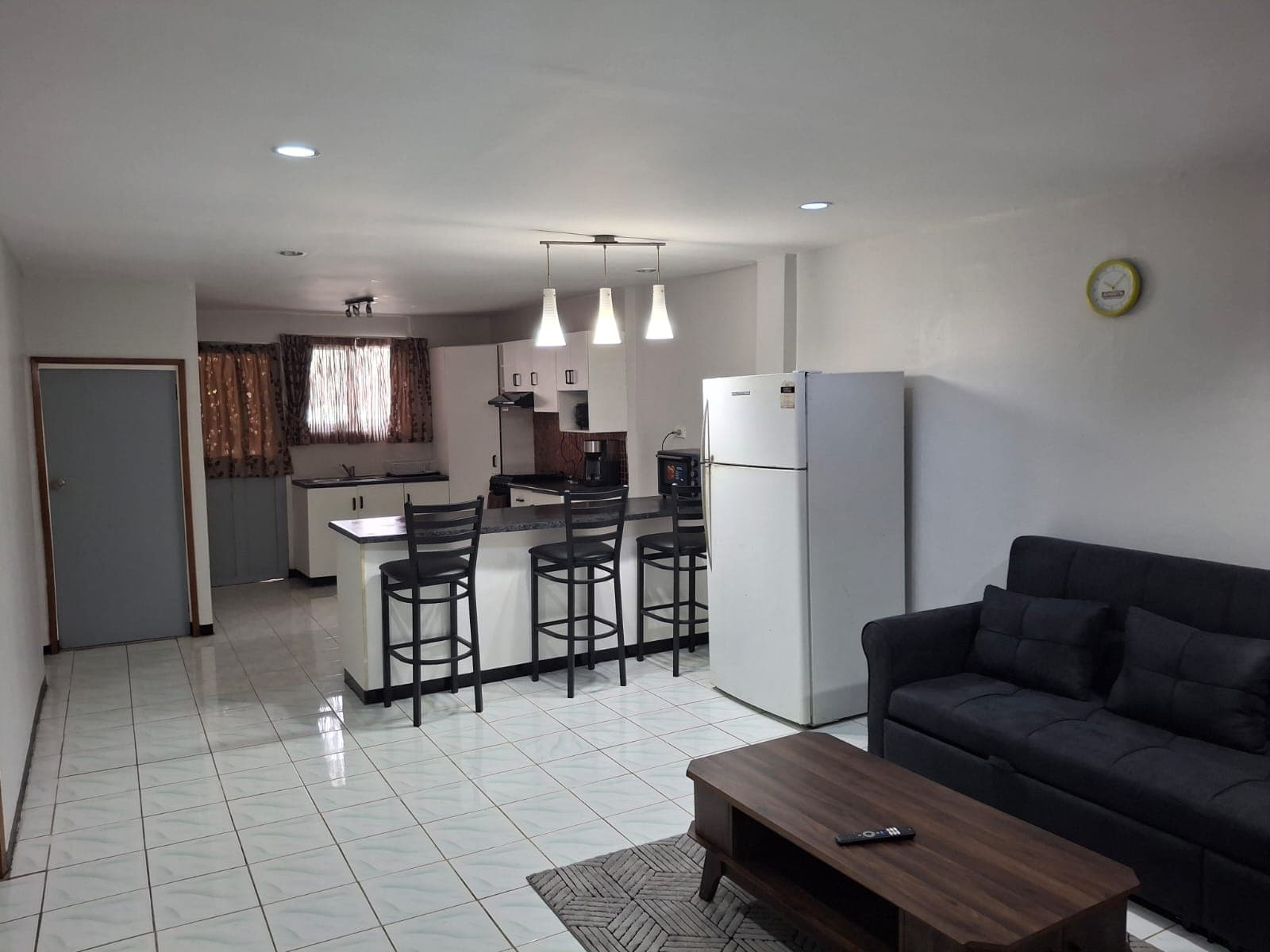 Open-plan living area with sofa, breakfast bar and kitchen